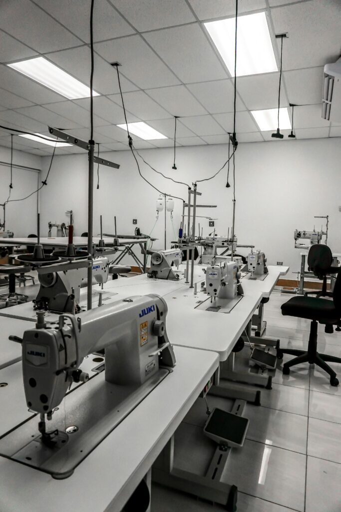 Industrial sewing machines in a well-lit factory room, ready for textile production.